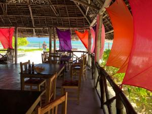 un restaurante con mesas y sillas en la playa en Blue Earth Beach Bungalow, en Jambiani