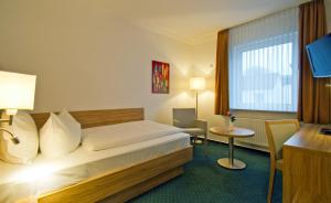 una camera d'albergo con letto, scrivania e finestra di Hotel Schaper a Celle