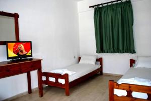 スタリスにあるKoula Apartmentsのベッド2台とテレビが備わる客室です。