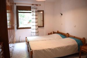 sypialnia z 2 łóżkami pojedynczymi i oknem w obiekcie Evagelia's Houses w mieście Votsi
