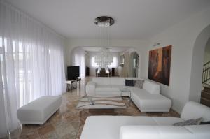 a living room with white furniture and a chandelier at Luxe Villa Livadia, 10 personen in Kandia