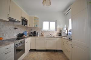 a kitchen with white cabinets and a sink at Luxe Villa Livadia, 10 personen in Kandia