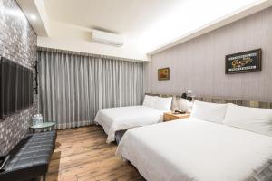 una camera d'albergo con due letti e un divano di Peach blossom B&B a Città di Taitung
