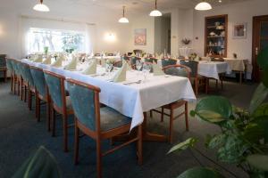 a long dining room with white tables and chairs at Pension & Restaurant Nordstern in Cottbus