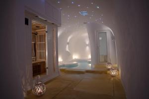 イメロヴィグリにあるDome Santorini Resort & Spaのバスルーム(壁に照明付きのバスタブ付)