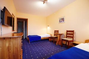 a hotel room with two beds and a tv at Ośrodek wypoczynkowy Kozioł in Kolno