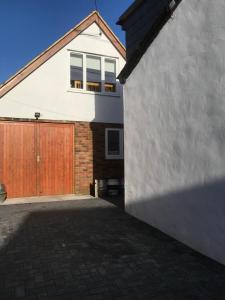 a white house with a wooden garage door at Studio above Worlds End microbrewery and behind the Crown Inn Pewsey in Pewsey