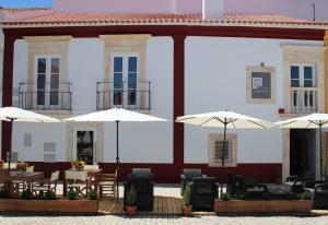 弗隆泰拉的住宿－Segredo d'Alecrim，前面有桌子和伞的建筑