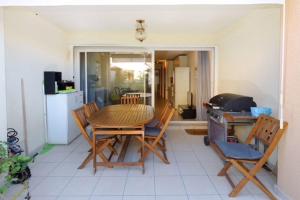 een keuken met een tafel en stoelen en een koelkast bij Résidence les Eucalyptus in LʼÎle-Rousse