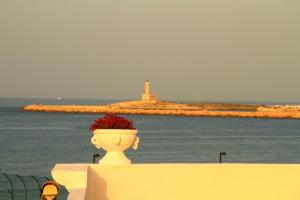 a vase sitting on a fence with a lighthouse in the background at Hotel Boutique Il Castellino Relais in Vieste