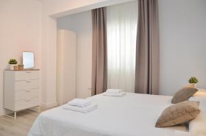 ein weißes Schlafzimmer mit einem weißen Bett und einer Kommode in der Unterkunft Canary Lofts Glorieta in Santa Cruz de Tenerife