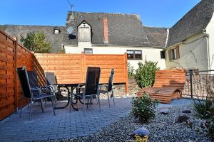 eine Terrasse mit einem Tisch, Stühlen und einem Zaun in der Unterkunft Moselhof Ferienwohnungen in Bruttig-Fankel