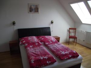 a bedroom with a bed with a red comforter and a chair at Apartman Kaszás City in Mosonmagyaróvár