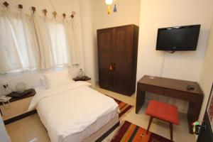 a small bedroom with a bed and a television at Khan Alwakala Hotel in Nablus