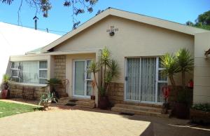 a house with palm trees in front of it at Anri Guesthouse in Bloemfontein