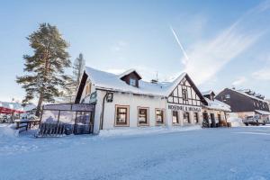 a building with snow on the ground in front of it at Penzion U Michala in Prášily