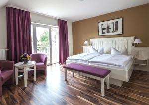 a bedroom with a large white bed and purple chairs at Pension Delia Will in Ahlbeck