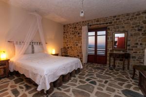 a bedroom with a bed and a stone wall at Ethaleia Hotel in Moúdhros