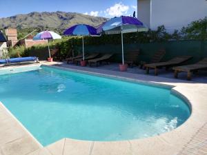 a swimming pool with umbrellas and picnic tables at Complejo Ayres de Funes in Potrero de los Funes