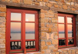 two windows in a brick building with a view of the water at Ethaleia Hotel in Moúdhros