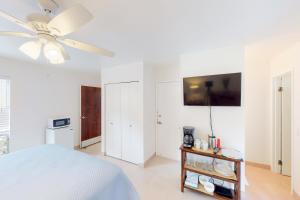 1 dormitorio blanco con 1 cama y ventilador de techo en Sandpiper #116b, en Princeville