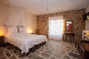 a bedroom with a bed in a room with a brick wall at Ethaleia Hotel in Moudhros