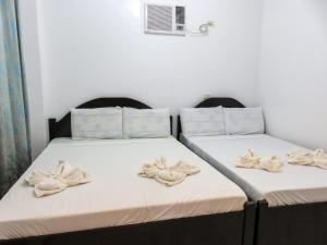 two beds in a room with towels on the beds at Nanette's Tourist Inn in Bantayan Island