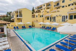 Corfu Aquamarine Hotel في نساكيون: مسبح امام الفندق فيه كراسي ومظلات