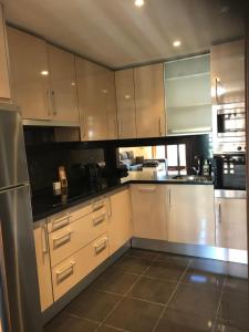 Una cocina con gabinetes blancos y un refrigerador de acero inoxidable. en Bahia de la Plata, en Estepona