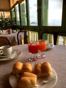 two rolls on a plate on a table with drinks at Hotel Badano sul Mare in Alassio