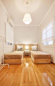 two beds in a large room with wooden floors at Chloe Boutique Apartments Metropolis in Athens