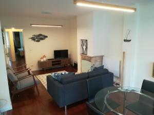 un salon avec un canapé bleu et une télévision dans l'établissement Matosinhos Beach Apartment, à Matosinhos