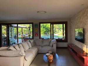 a living room with a white couch and a tv at Casa 4 Quartos Praia do Forte in Praia do Forte
