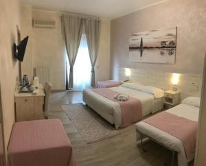 a hotel room with two beds and a window at Fiumicino Airport B&B Deluxe in Fiumicino