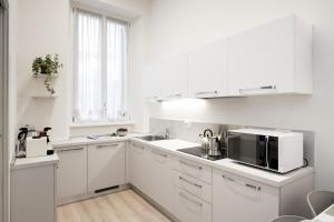 - une cuisine blanche avec évier et four micro-ondes dans l'établissement Duomo apartment, à Vérone