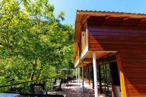 un portico di un edificio in legno con sedie e ombrellone di Ayder İmamoğlu Apart Otel ad Ayder Yaylasi