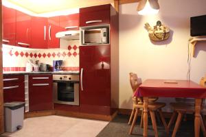 a kitchen with red cabinets and a table with chairs at Neves in Val Thorens