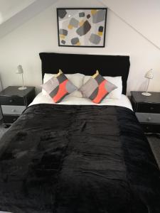a bedroom with a bed with pillows and two tables at Havering Hotel in Romford