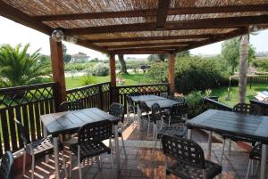eine Terrasse mit Tischen und Stühlen unter einer hölzernen Pergola in der Unterkunft Villa Primavera in Latina