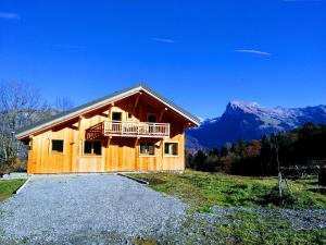 a wooden house on a hill with mountains in the background at Chalet "Le mas devant" in Morillon