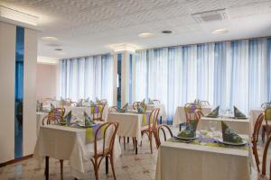 ミザーノ・アドリアーティコにあるHotel Normaの白いテーブルと椅子、窓のあるレストラン