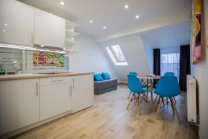 a kitchen with white cabinets and a table with blue chairs at Adonis Apartments in Świnoujście