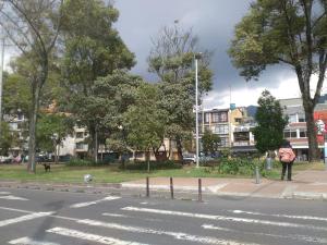 a person with an umbrella standing on the side of a street at Alojate y Descansa in Bogotá