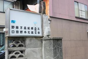 un cartel en una pared al lado de un edificio en Oyado Shogoin en Kyoto