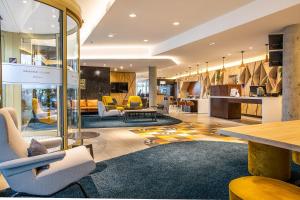 a lobby with yellow chairs and tables in a building at Hôtel Mercure Paris Gennevilliers in Gennevilliers