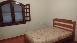 a small bed in a room with a window at Casa de Praia Loan in Caraguatatuba