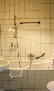 y baño con bañera, aseo y lavamanos. en Hotel Heidekrug en Grünplan