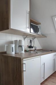 cocina con armarios blancos y microondas en Ferienwohnung Stadt- und Hafennähe, en Fehmarn