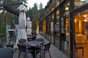 a patio with chairs and tables and umbrellas at Belvilis Hotel in Molėtai