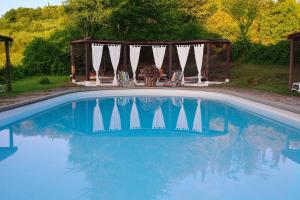 uma piscina com um gazebo, uma mesa e cadeiras em La Striscia Wine Resort em Arezzo